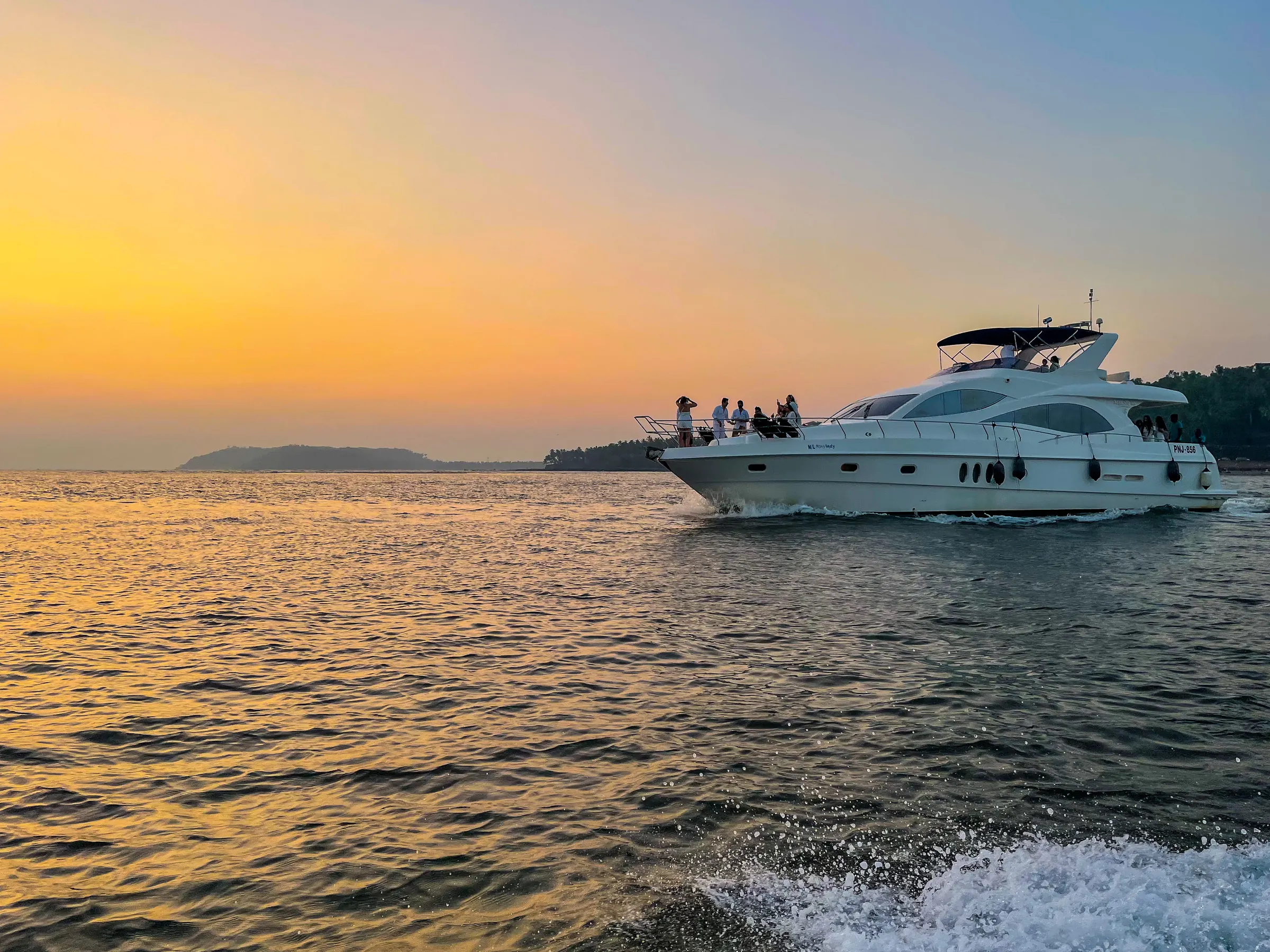 A Yacht Life Goa yacht cruising at dusk with guests on the upper deck